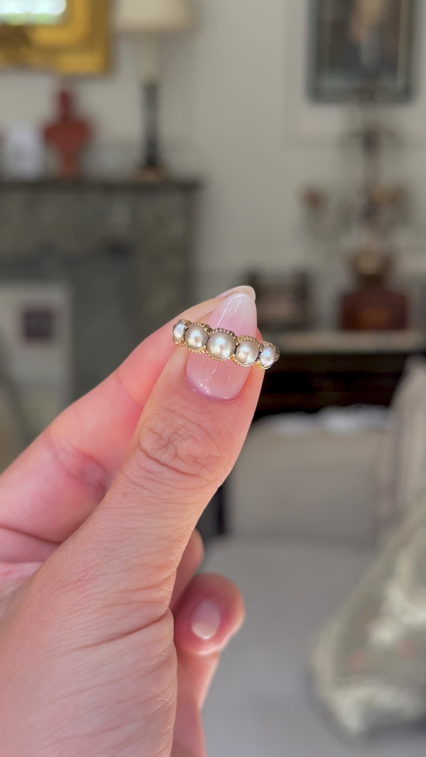 antique georgian pearl half hoop ring held in fingers and rotated to give perspective, front view.