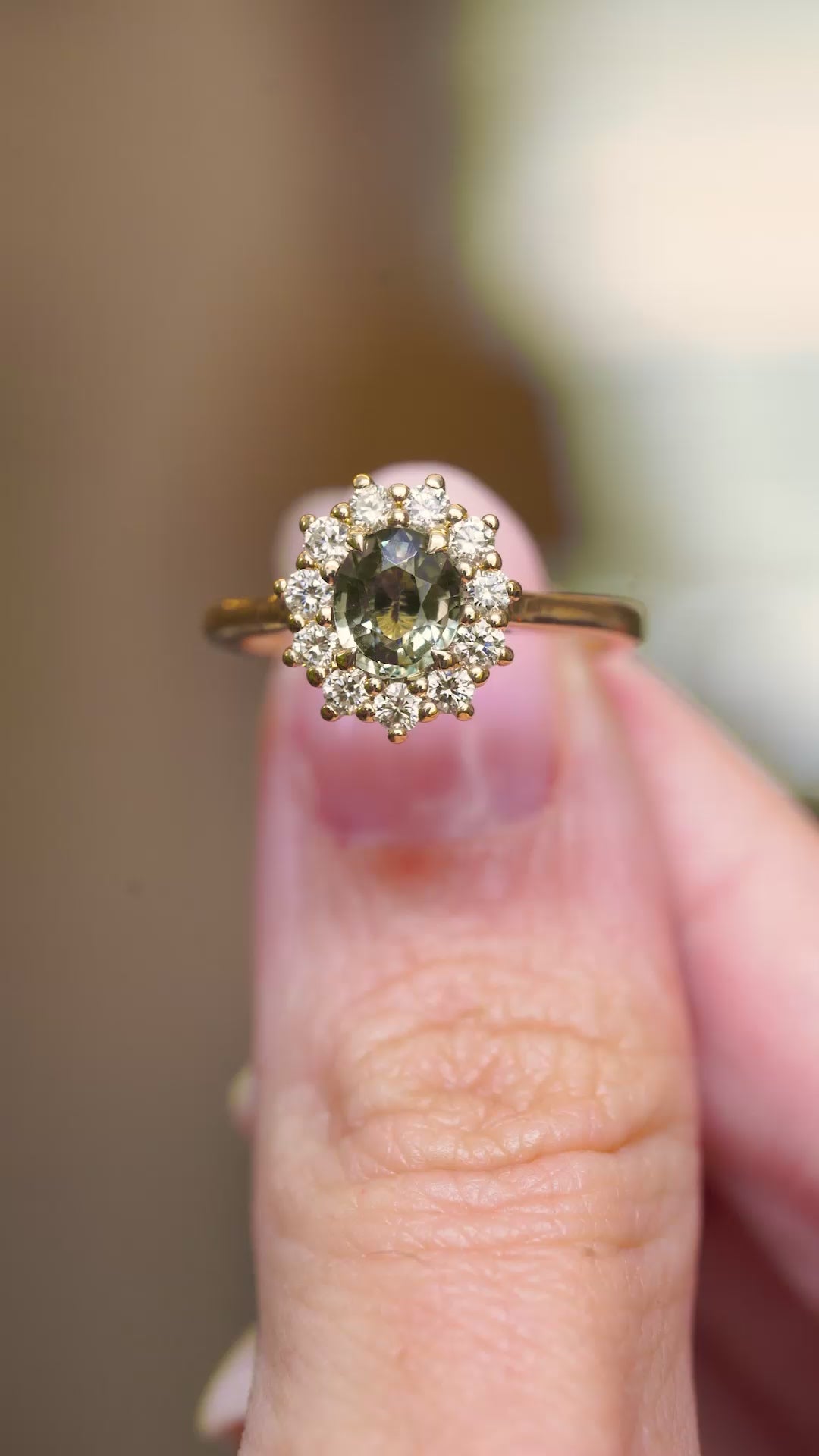 A video of a green sapphire halo cluster engagement ring with diamonds in an antique-inspired yellow gold design.