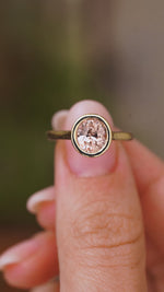 A close up video of an Antique-inspired,  sapphire solitaire engagement ring, rotated slowly to showcase the pinkish-brown colour of the Sri Lankan sapphire and the yellow gold setting and band.