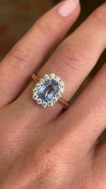 Video of an Antique-inspired, blue sapphire and diamond cluster engagement ring in gold worn on a hand.