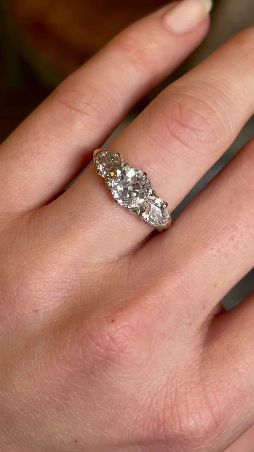 Antique Victorian three-stone with cushion-cut and pear-cut diamonds ring on a hand moved around do show details. 