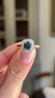 Antique Art Deco sapphire and diamond cluster engagement ring showcasing a blue sapphire centre stone and geometric diamond cluster design, held by hand to highlight the setting and craftsmanship.