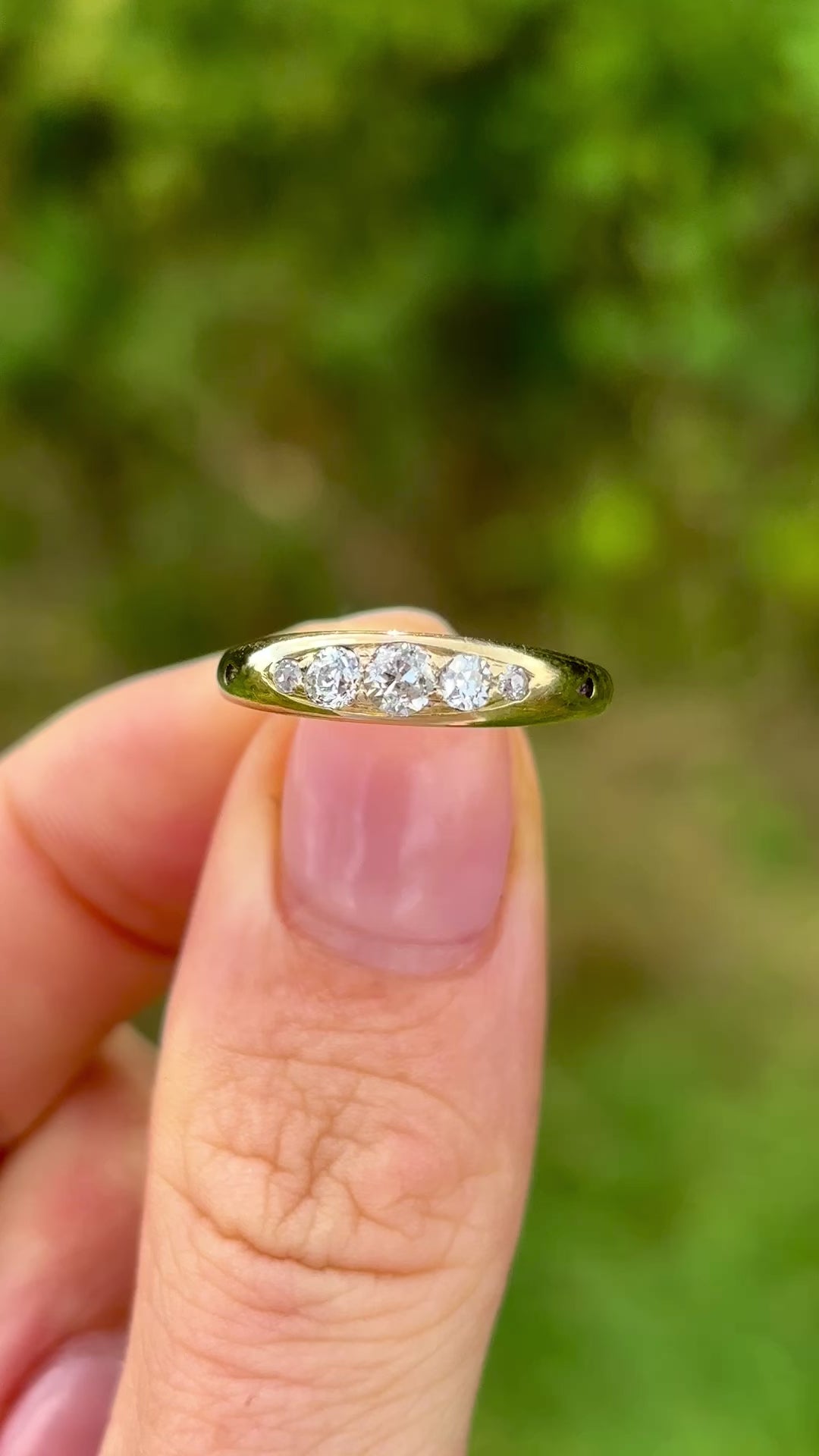 Antique, Edwardian five-stone diamond ring front held in fingers