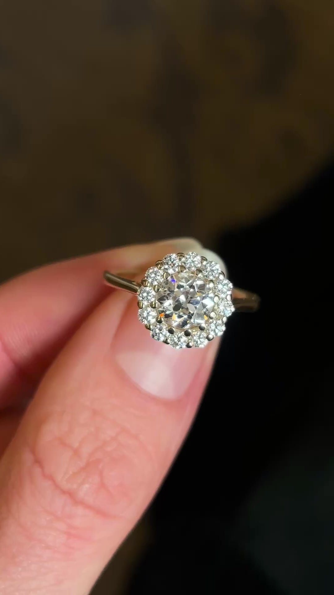 Diamond cluster yellow gold engagement ring held and rotated to show fine details of diamonds and setting. 