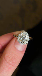 Diamond cluster yellow gold engagement ring held and rotated to show fine details of diamonds and setting. 
