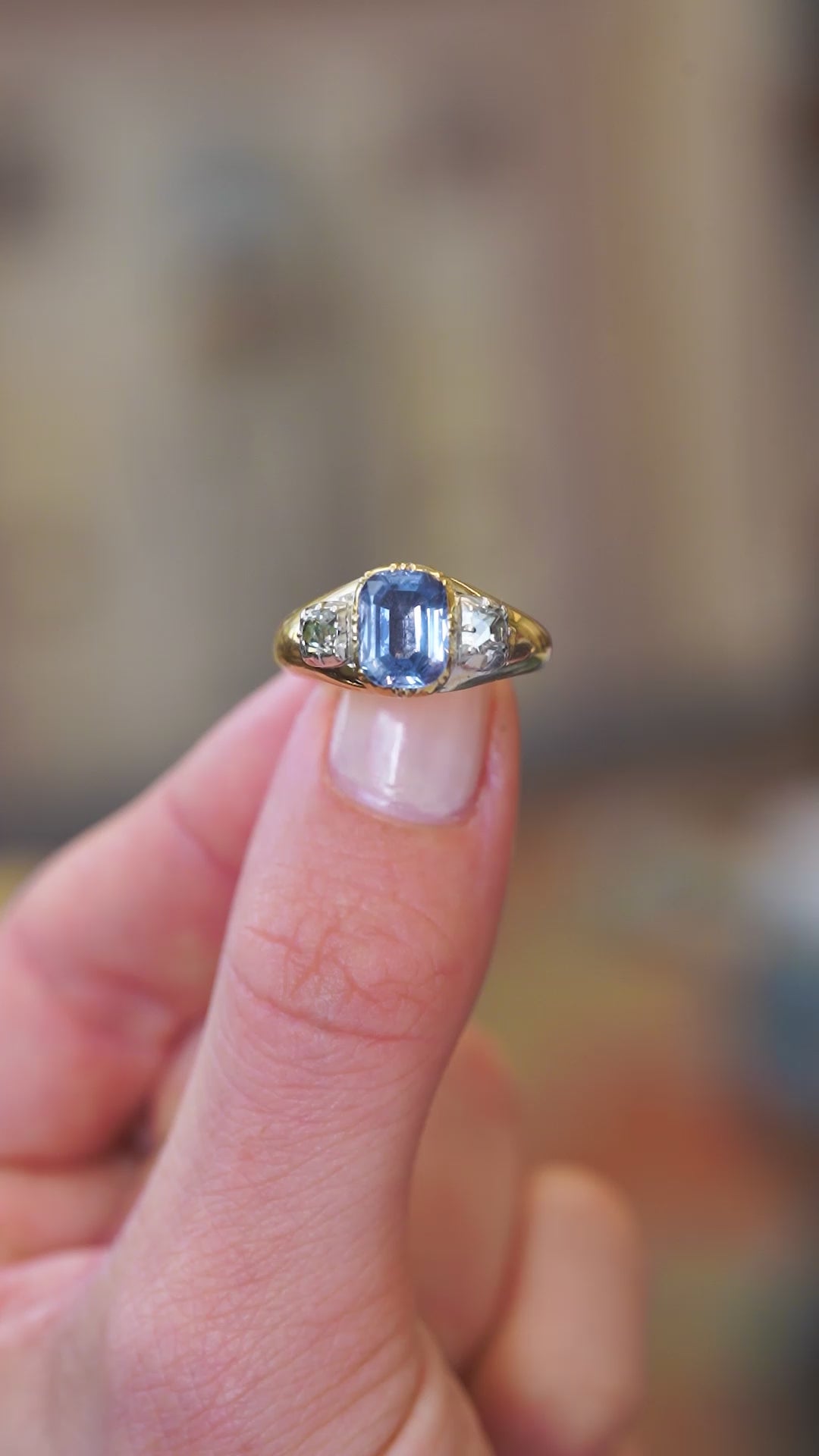 Sapphire ring with diamond side stones showing subtle sparkle and antique character.