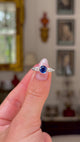 Art Deco sapphire and diamond engagement ring, held in fingers and rotated to give perspective, front view. 