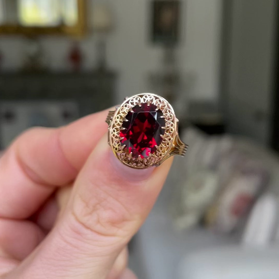 Belle Époque red garnet ring, held in fingers and moved around to give perspective.