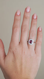 A video of the vintage ruby and diamond ring on a finger, capturing the gemstone's vivid colour and the brilliance of its diamond halo.