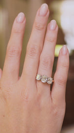 A video of a vintage diamond three-stone ring on a yellow gold band worn on the hand.