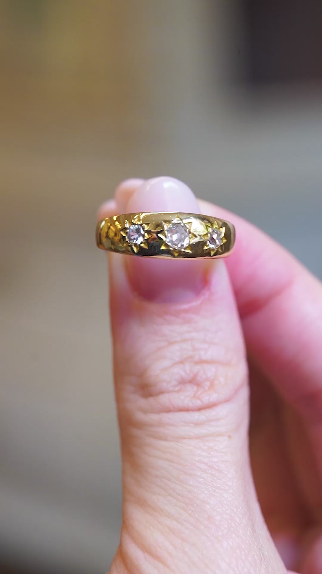 Close detail of antique Edwardian old-mine cut diamond gypsy ring between fingers.