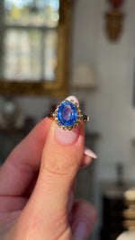 sapphire and yellow gold engagement ring held in fingers and moved around to give perspective. 