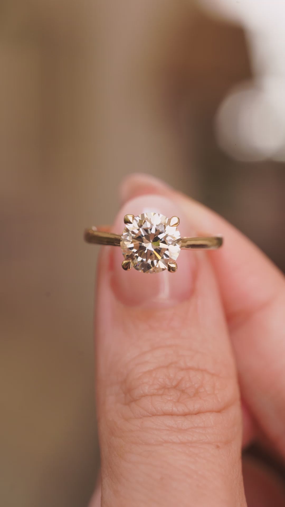 video of Antique-inspired, Light brown diamond solitaire engagement ring in yellow gold held in between fingers and turned.