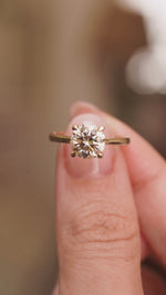 video of Antique-inspired, Light brown diamond solitaire engagement ring in yellow gold held in between fingers and turned.