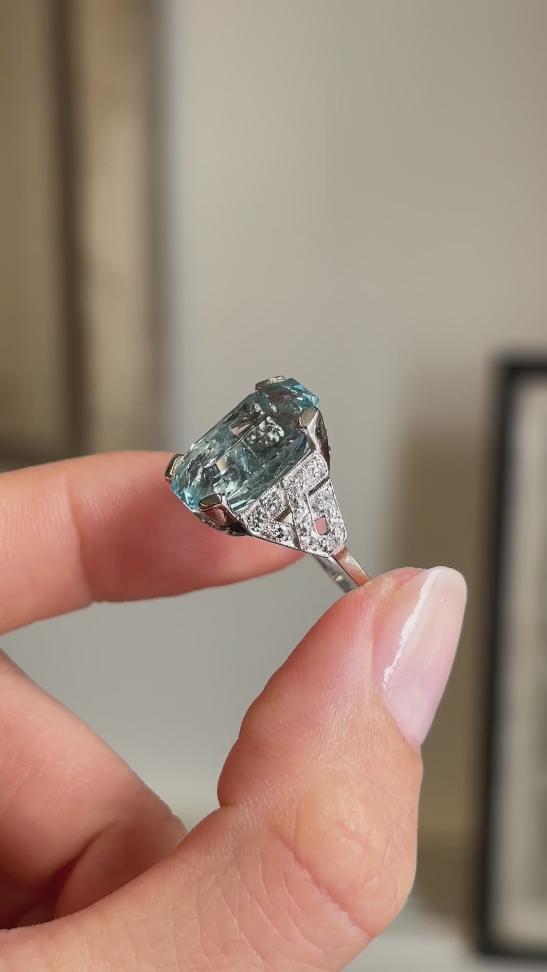 Detailed video of an antique Art Deco aquamarine and diamond cocktail ring in platinum held between fingers, displaying the vivid blue aquamarine centre stone, sparkling diamond accents and vintage interior setting.