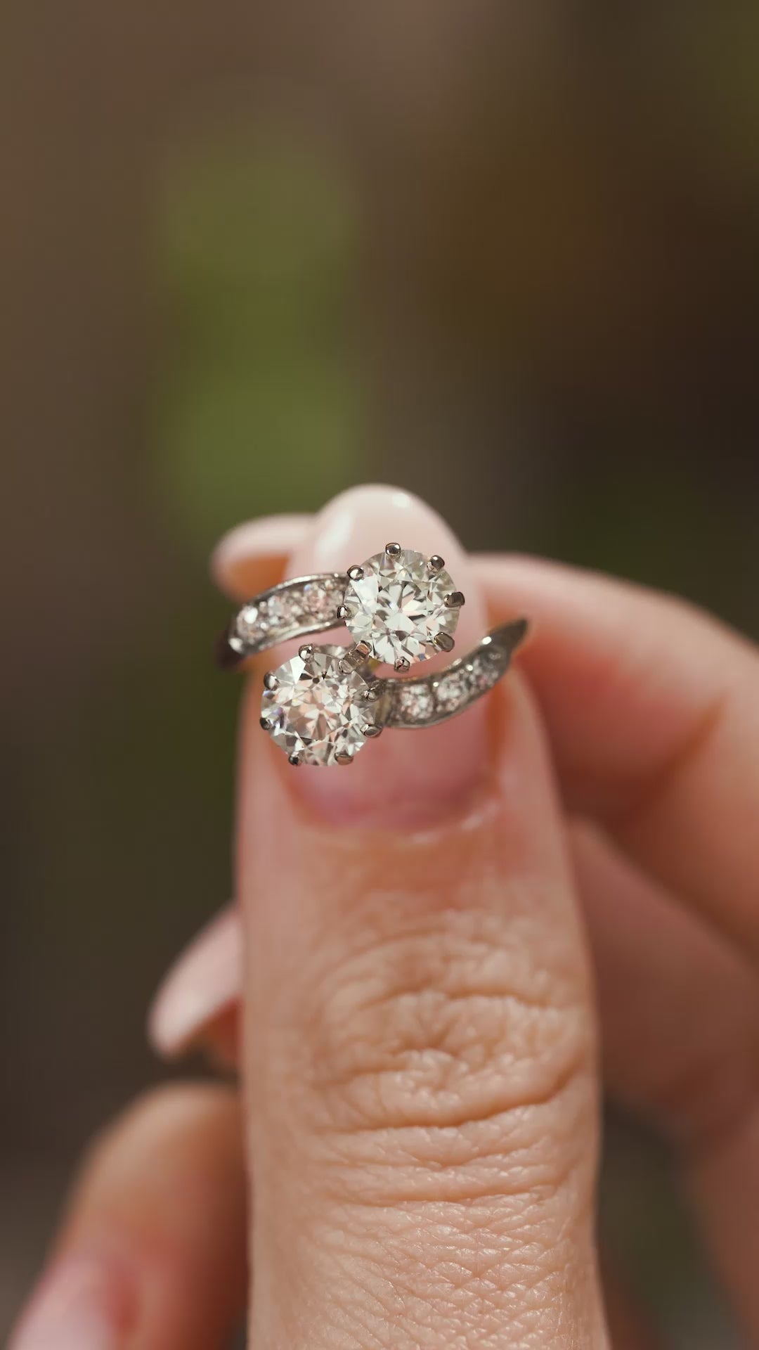 A video of fingers holding Antique, Edwardian diamond toi et moi engagement ring and turning to show different angles.