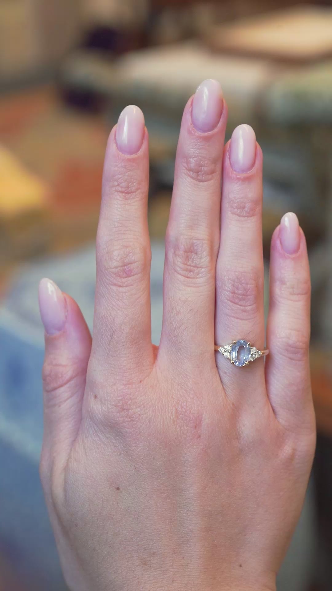 Pale blue sapphire and diamond cluster tre-foil engagement ring worn on hand with slow movements.