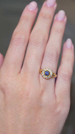 A video of an outstretched hand wearing an Antique, Victorian blue sapphire and old mine-cut diamond yellow gold cluster engagement ring whilst the fingers move.