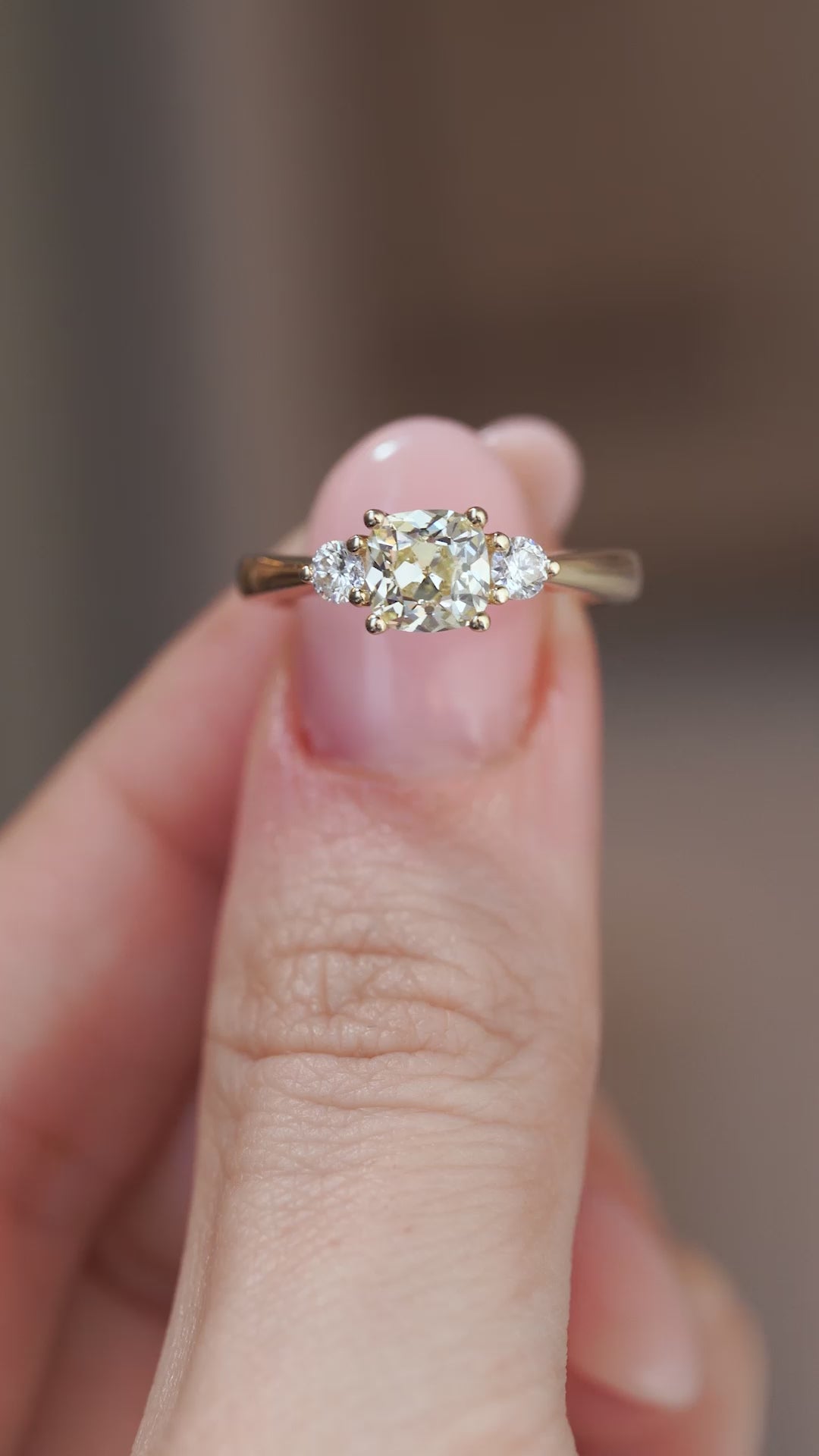 A close-up video of the three-stone diamond ring held between fingers, showcasing the diamonds' brilliance and sparkle.