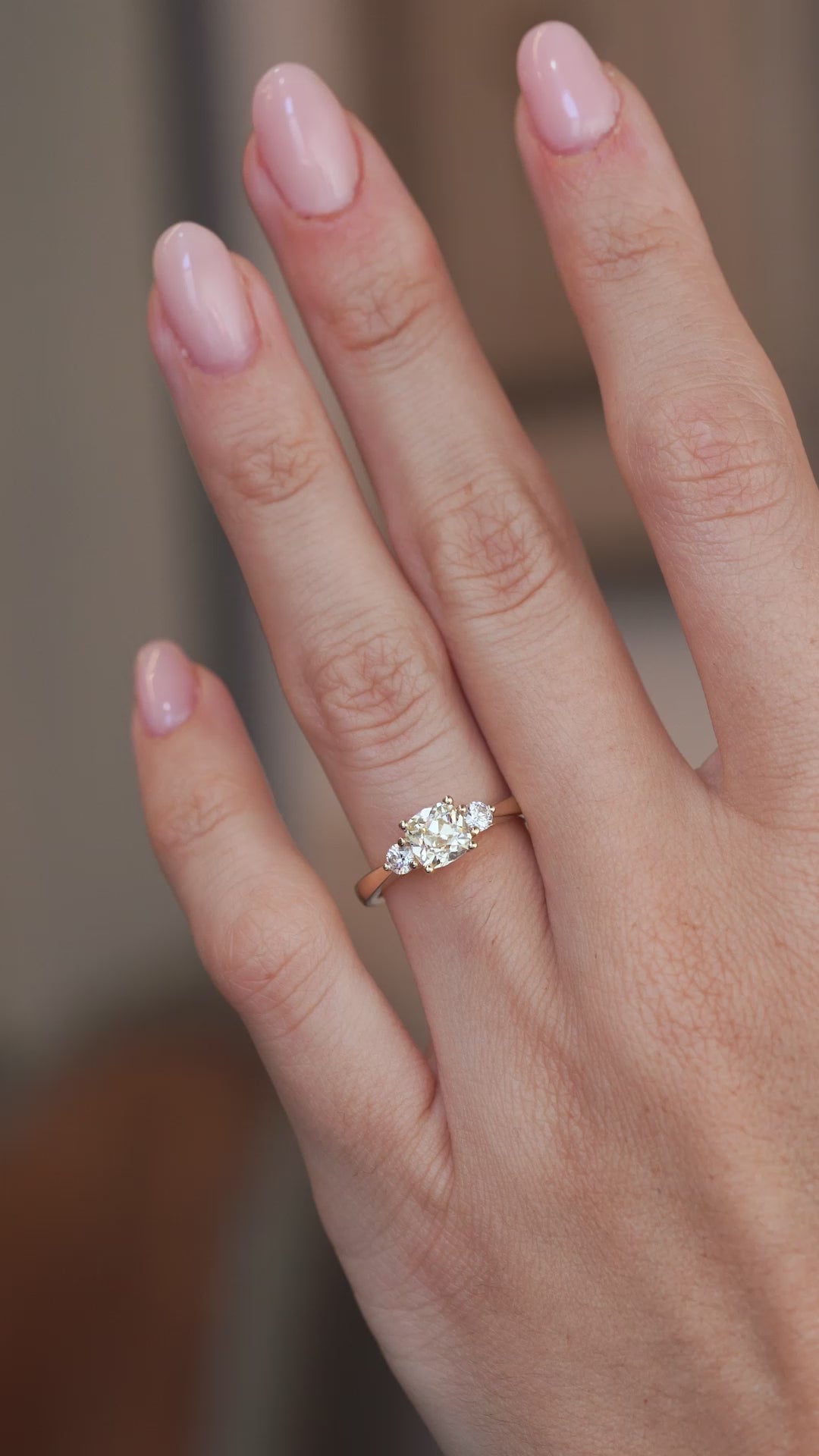 A video of the cushion-cut diamond engagement ring worn on a finger, capturing its sparkle and delicate yellow gold setting.