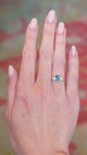 Teal sapphire and diamond cluster tre-foil engagement ring worn on hand with subtle movements.