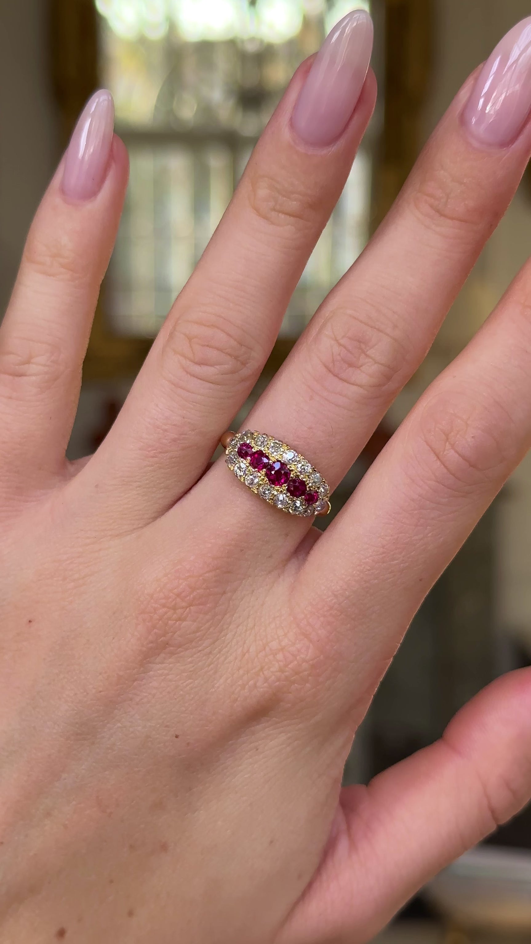 Ruby and diamond cluster engagement ring worn on hand and moved around to give perspective.