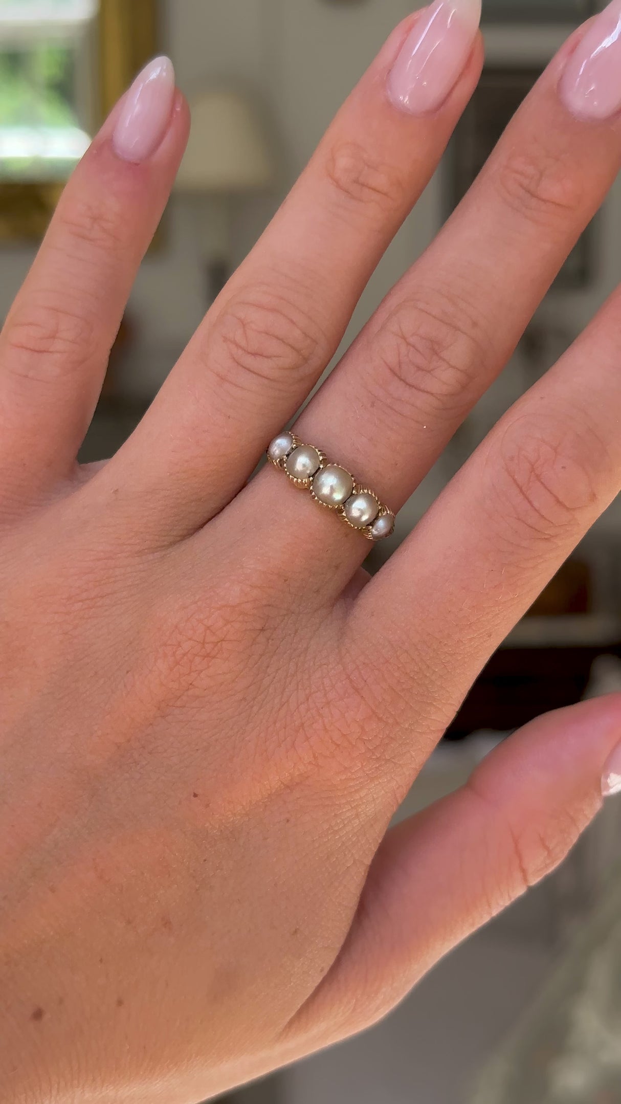 antique georgian pearl half hoop ring worn on hand and moved away from lens to give perspective, front view.