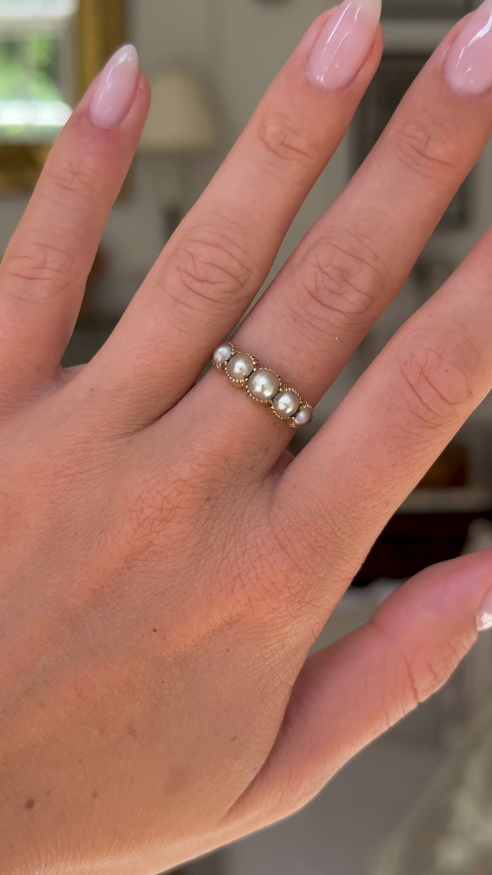 antique georgian pearl half hoop ring worn on hand and moved away from lens to give perspective, front view.