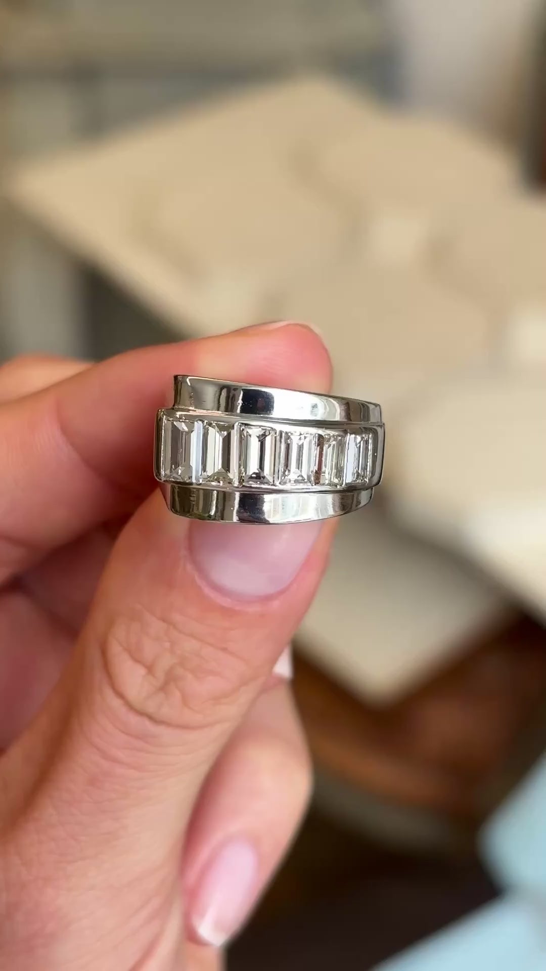 A close up video of a platinum Vintage, 1940s channel-set baguette-cut diamond ring rotated to showcase the profiles of the ring