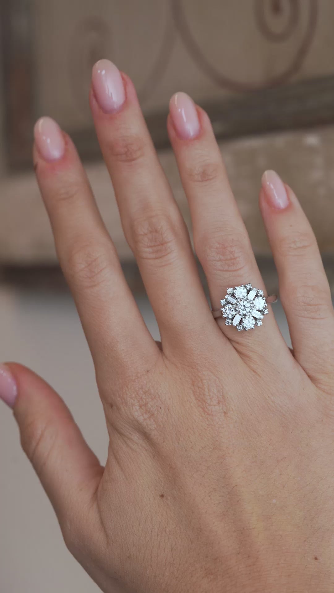 A video of the diamond cluster ring worn on a finger, capturing the sparkle of the round brilliant-cut and baguette-cut diamonds.