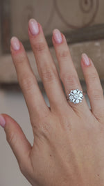A video of the diamond cluster ring worn on a finger, capturing the sparkle of the round brilliant-cut and baguette-cut diamonds.