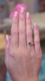 Pine green sapphire and diamond engagement ring worn on hand with gold band showing subtle motion.