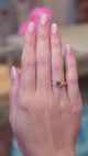 Pine green sapphire and diamond engagement ring worn on hand with gold band showing subtle motion.