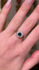 Antique sapphire diamond cluster ring, worn on hand and moved away from lens to give perspective, front view. 