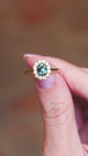 Sapphire and diamond cluster ring showing central green stone and surrounding diamond sparkle.