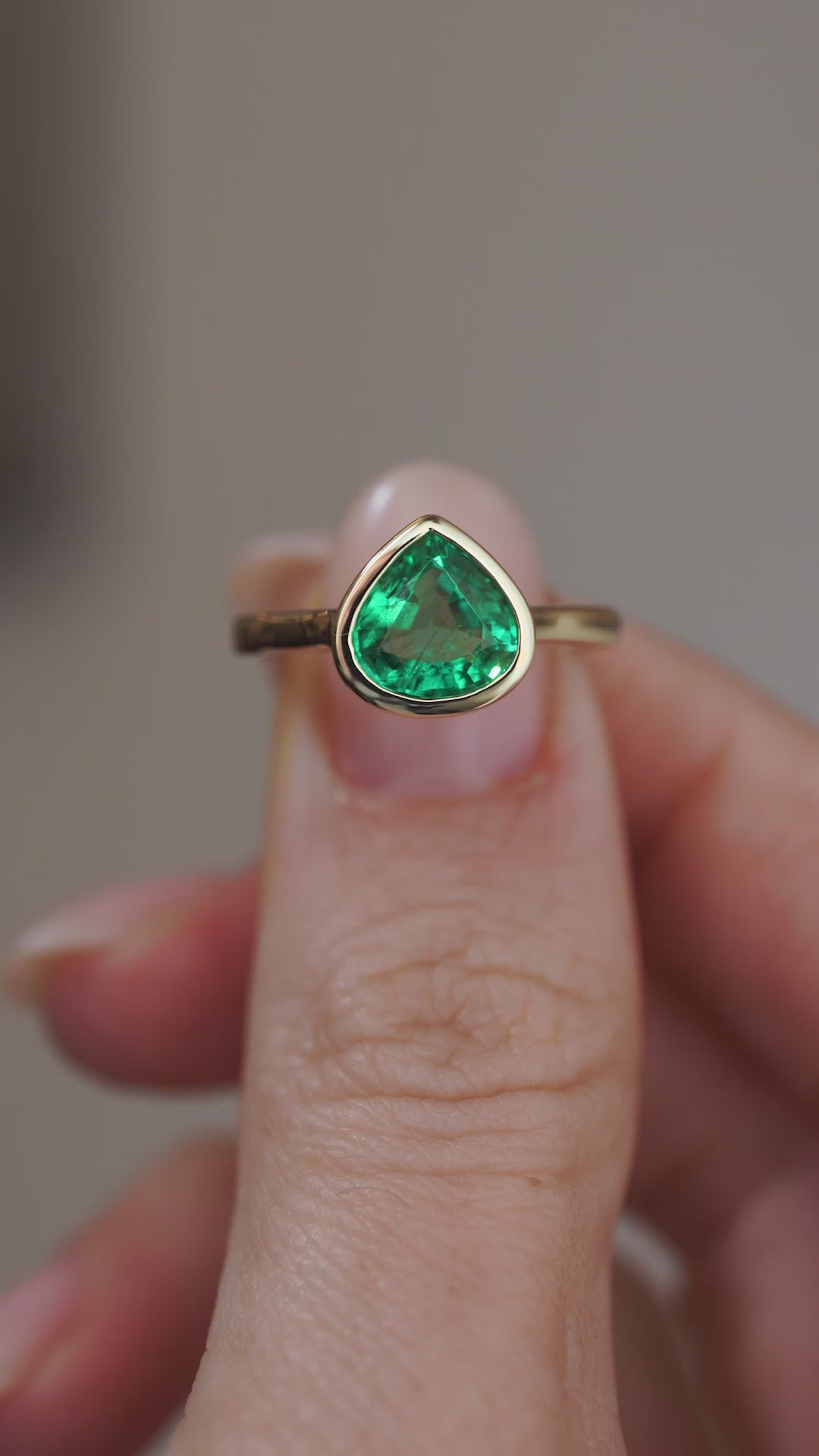 Video presenting the vintage-inspired emerald ring balanced on a fingertip for a clear face-on view of its pear shape.