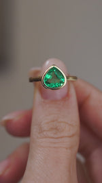Video presenting the vintage-inspired emerald ring balanced on a fingertip for a clear face-on view of its pear shape.