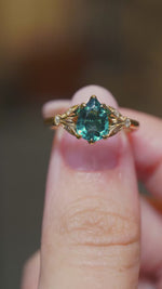 A video of the Front view of a teal tourmaline ring with decorative diamond-set shoulders