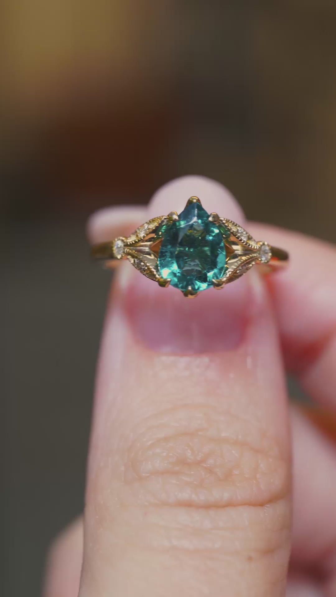 A video of the Front view of a teal tourmaline ring with decorative diamond-set shoulders