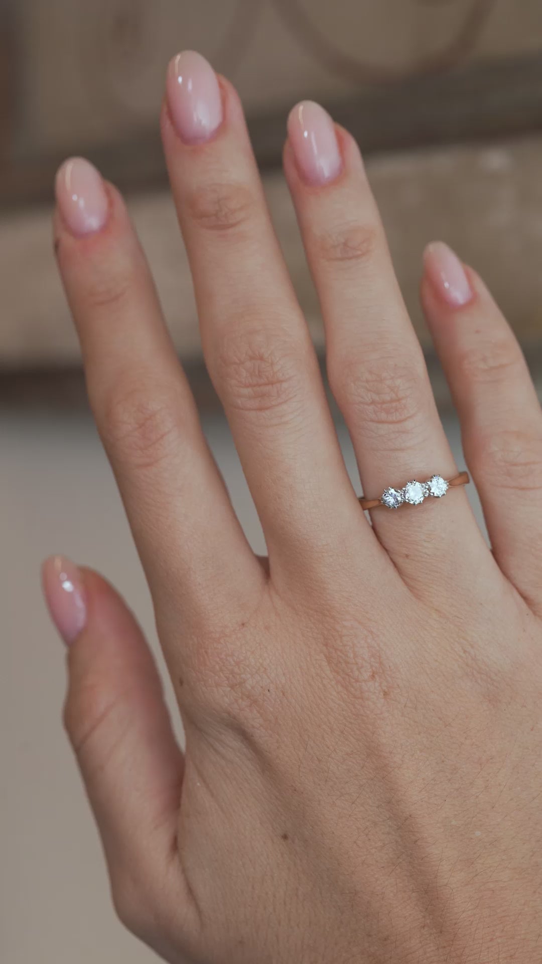 A video of the old-cut diamond engagement ring worn on a finger, capturing the sparkle of the three diamonds.