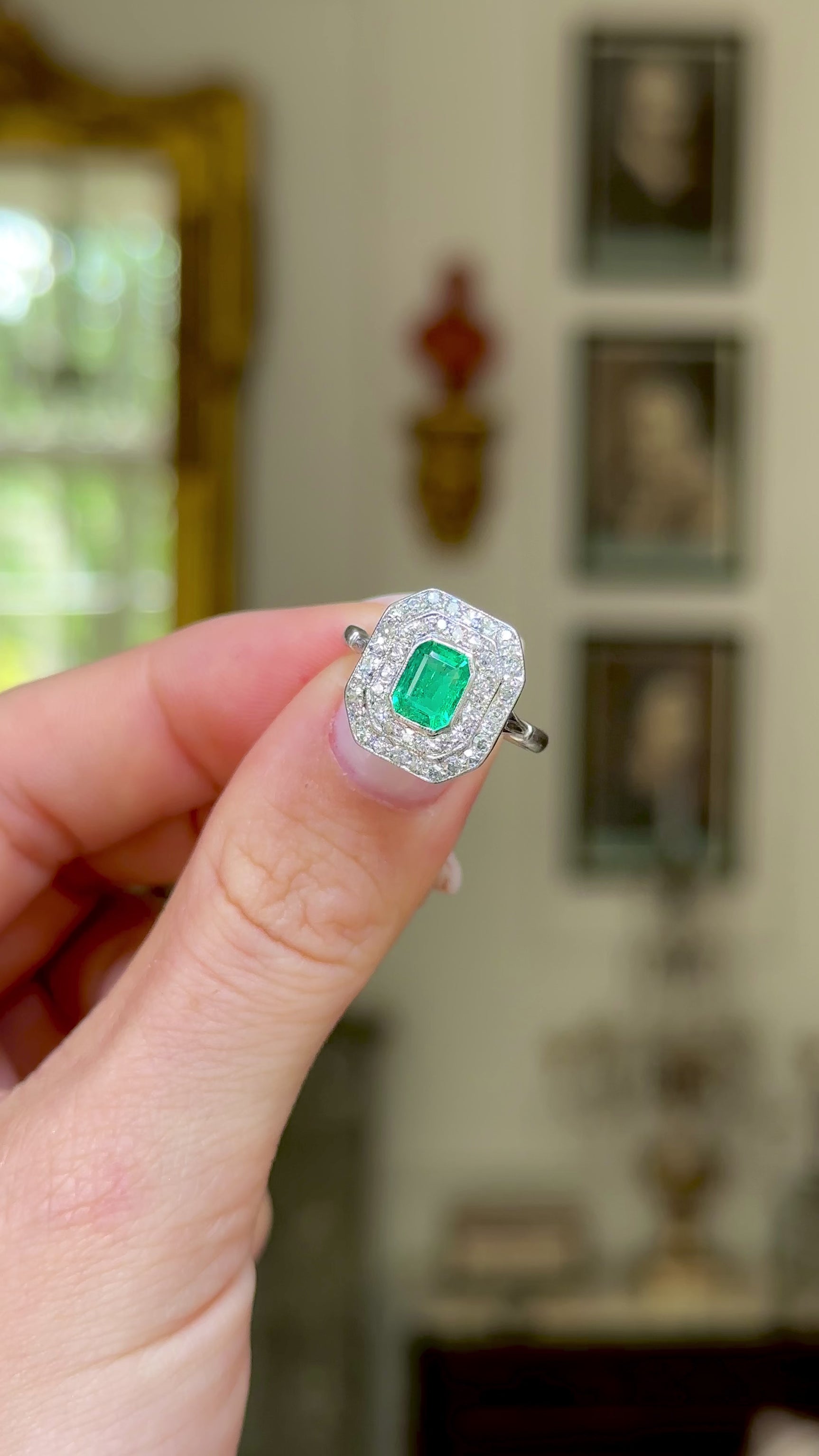 Vintage emerald and diamond cluster ring, held in fingers and moved around to give perspective.