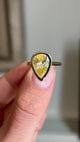 Close-up video of an antique-inspired yellow gold sapphire solitaire ring highlighting a large pear-cut Sri Lankan sapphire in a polished rub-over setting, revealing exceptional brilliance and warm yellow hues.