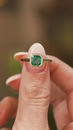 A video of fingers holding Antique-inspired, Emerald solitaire engagement ring in yellow gold and turning to show angles.