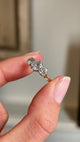 Close up video of an Antique, Edwardian gold three-stone ring, held between two fingers and rotated slowly to display the old-cut diamonds. 