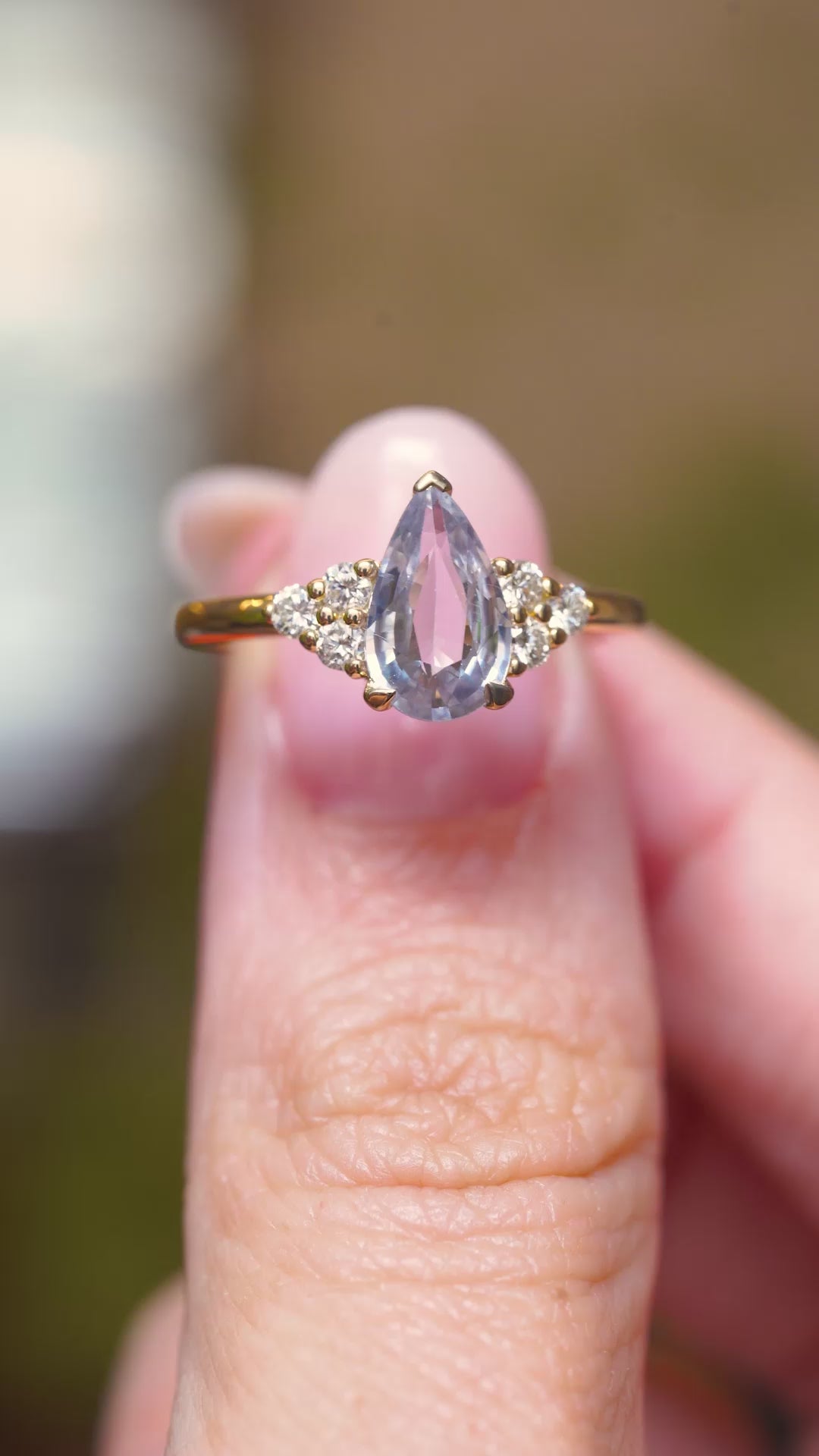 A close-up video of a vintage-inspired yellow gold engagement ring featuring a white pear-cut sapphire.