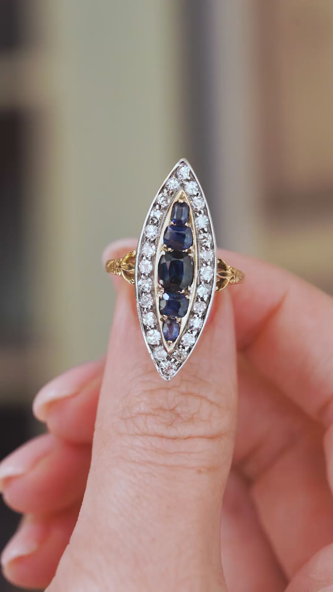 Video close-up on a fingertip showing the five blue sapphires, bright diamond border and detailed Victorian metalwork.