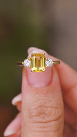 A video of an Antique-inspired, Yellow sapphire and diamond three-stone yellow gold engagement ring held in between the fingers and slowly turned to show off different angles of the ring.
