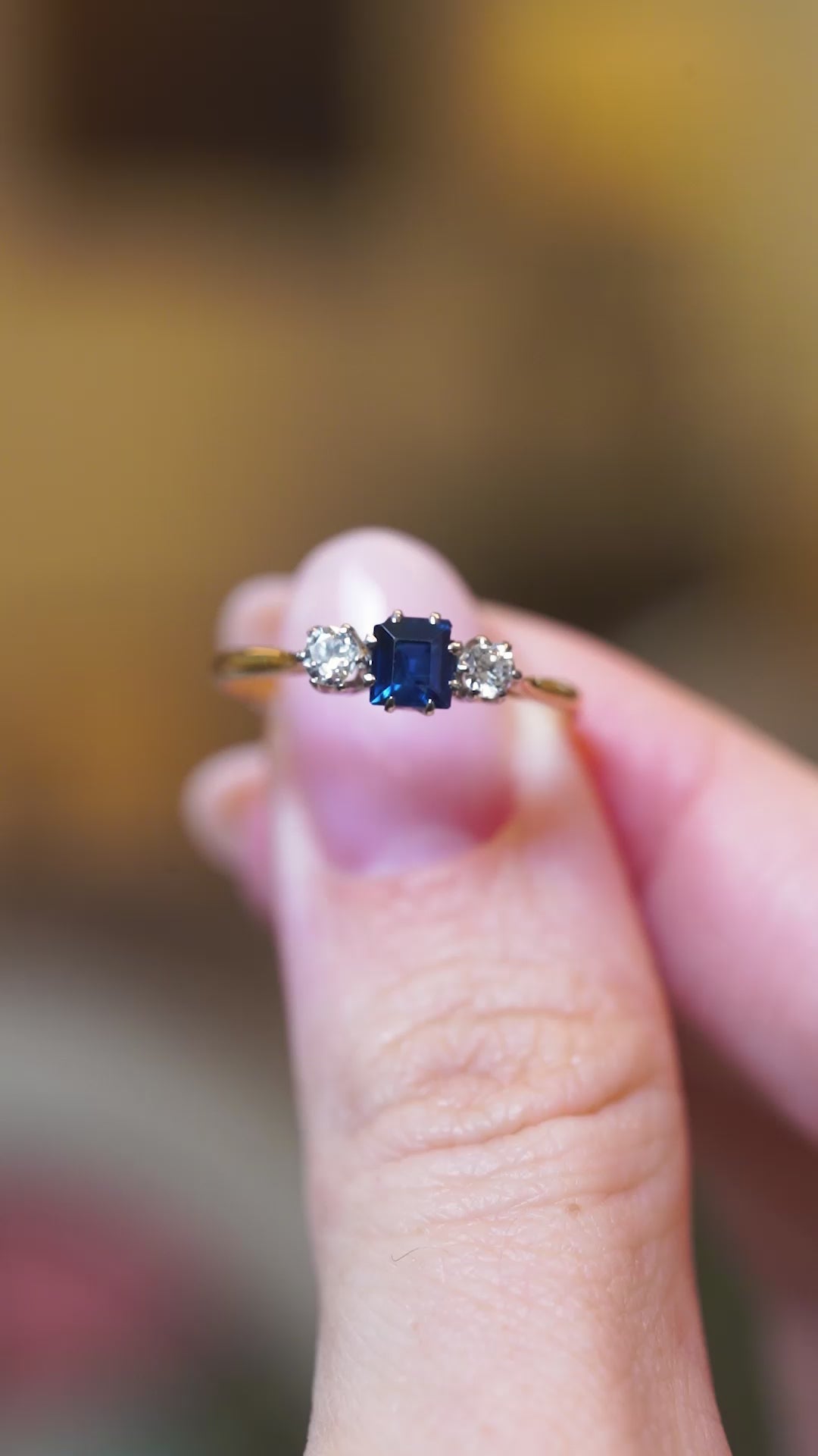 Close detail video of antique 1920s sapphire and diamond three-stone ring with sparkling diamonds.