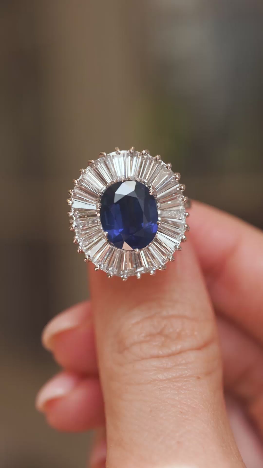 Video close-up of a 1950s sapphire ballerina ring balanced on a fingertip, displaying its statement diamond cluster design.