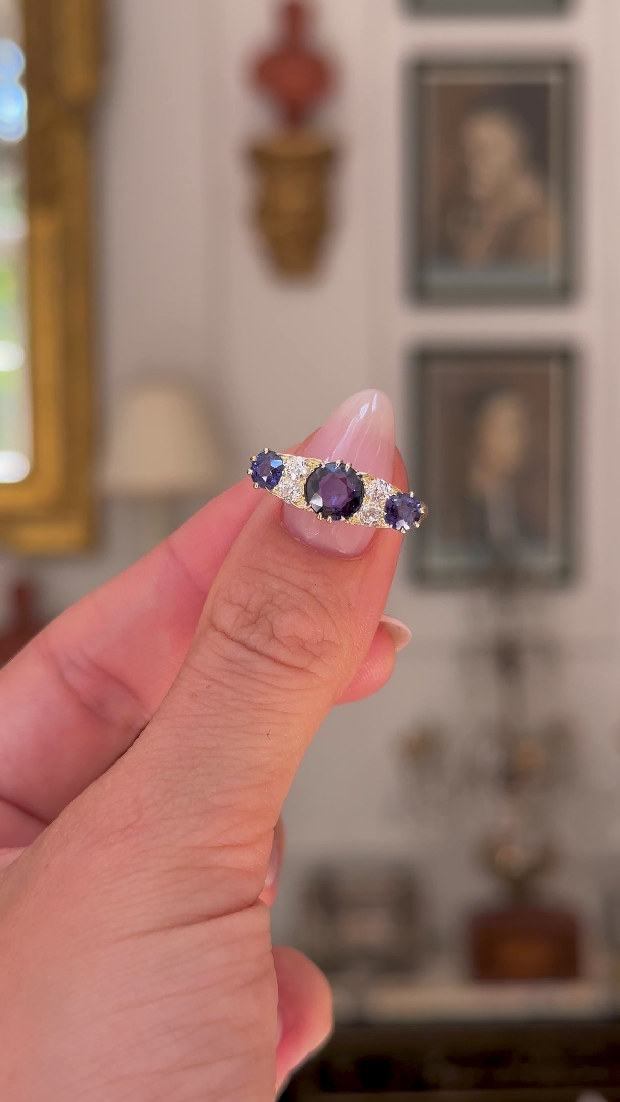 Antique purple sapphire and diamond engagement ring, held in fingers and rotated to give perspective, front view.